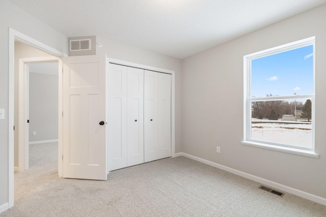 unfurnished bedroom featuring light colored carpet and a closet