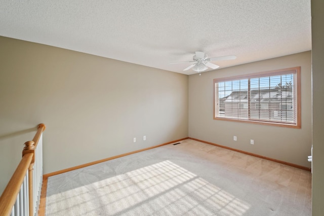 empty room featuring light carpet, ceiling fan, and a textured ceiling