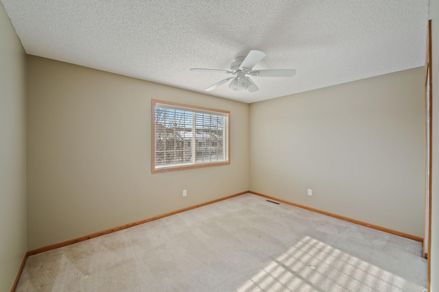 empty room featuring light carpet, ceiling fan, and a textured ceiling