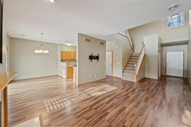 unfurnished living room featuring a textured ceiling, a chandelier, and hardwood / wood-style flooring