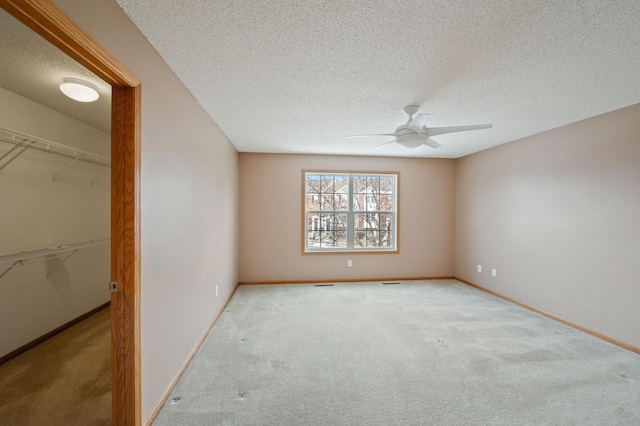 carpeted spare room with ceiling fan and a textured ceiling