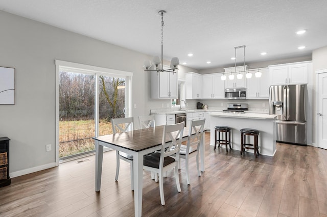 dining room featuring plenty of natural light, sink, dark hardwood / wood-style flooring, and a notable chandelier