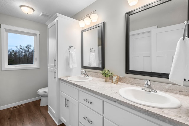 bathroom with toilet, vanity, a textured ceiling, and hardwood / wood-style flooring