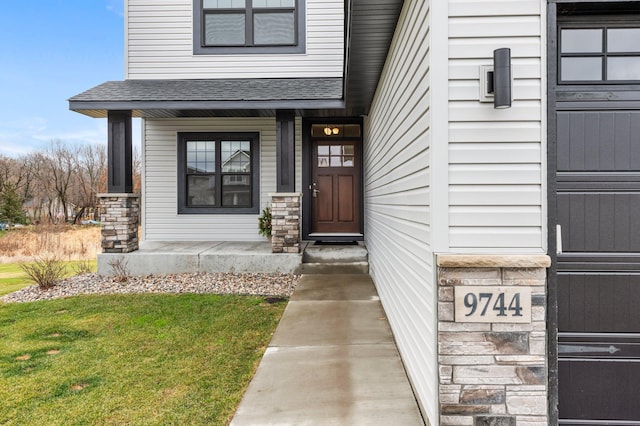 entrance to property with covered porch and a yard