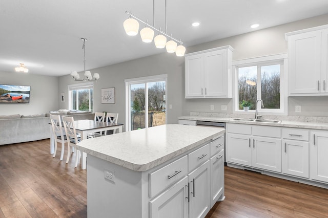 kitchen with decorative light fixtures, sink, white cabinetry, and a center island