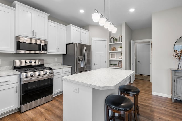 kitchen with a center island, hanging light fixtures, a kitchen breakfast bar, stainless steel appliances, and white cabinets