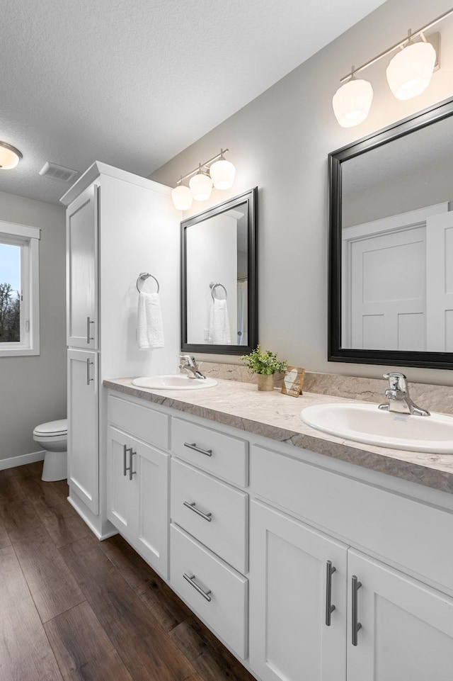 bathroom featuring hardwood / wood-style floors, toilet, vanity, and a textured ceiling