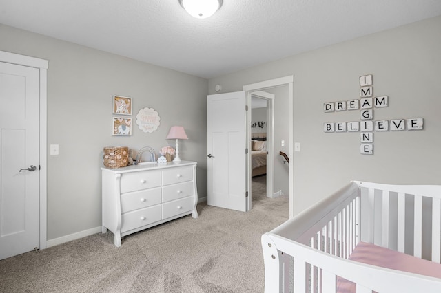 bedroom featuring a textured ceiling, light colored carpet, and a crib