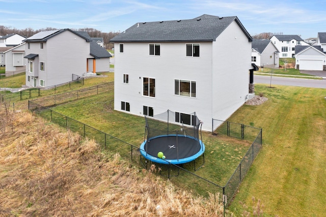 back of house featuring a trampoline and a yard