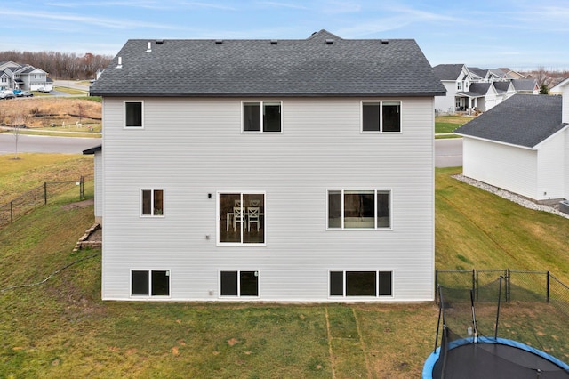 rear view of property with a lawn and a trampoline