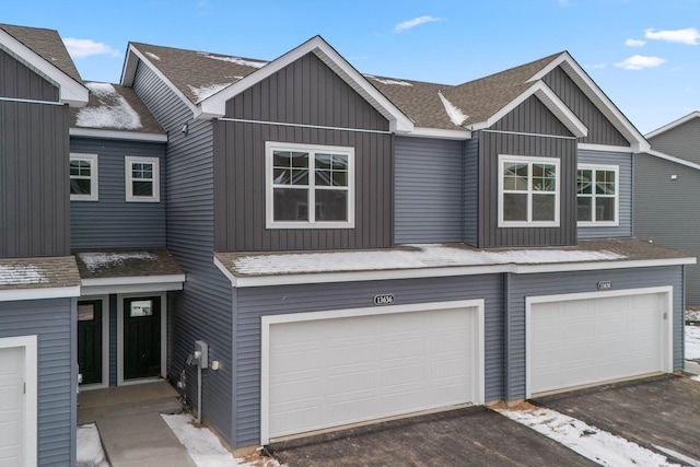 townhome / multi-family property featuring a garage, board and batten siding, and roof with shingles