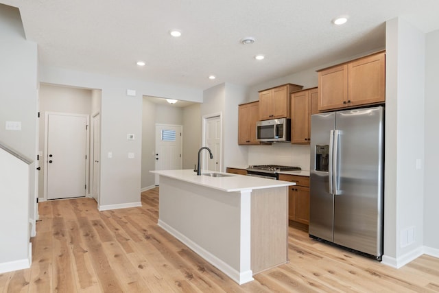 kitchen featuring visible vents, light wood-type flooring, an island with sink, appliances with stainless steel finishes, and a sink