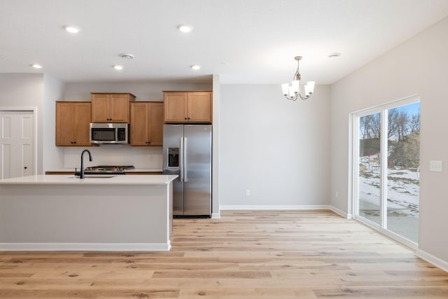 kitchen featuring light countertops, light wood-type flooring, recessed lighting, appliances with stainless steel finishes, and brown cabinetry