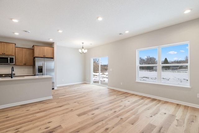 kitchen featuring appliances with stainless steel finishes, light wood-type flooring, baseboards, and a sink