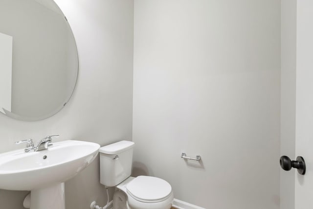 bathroom featuring toilet, baseboards, and a sink