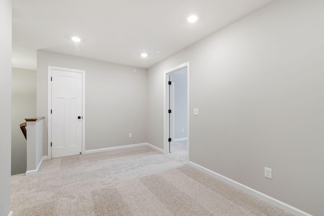 spare room with recessed lighting, baseboards, and light colored carpet