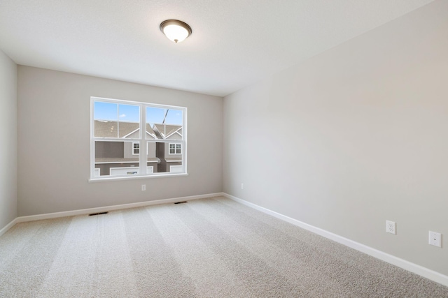 spare room with baseboards, visible vents, and light carpet