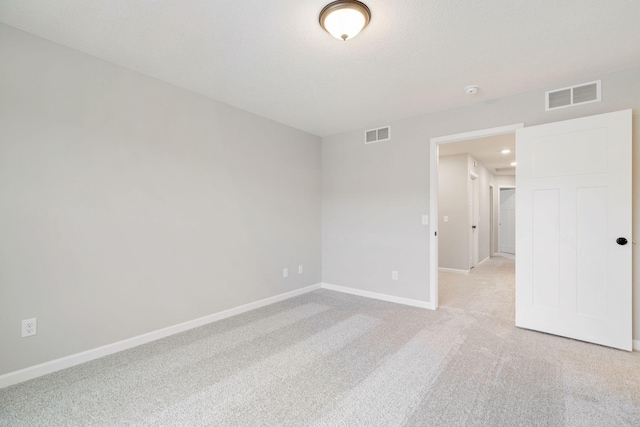 spare room with light colored carpet, baseboards, and visible vents