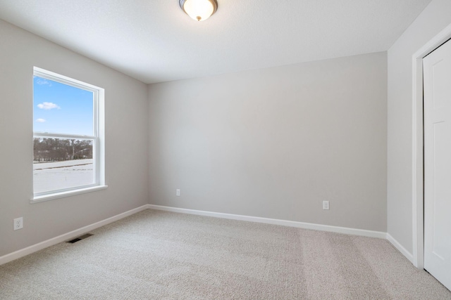 carpeted spare room with visible vents and baseboards