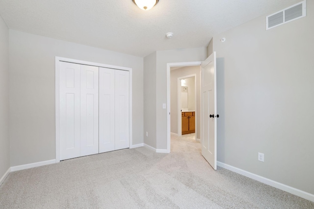 unfurnished bedroom with light colored carpet, visible vents, a closet, and baseboards