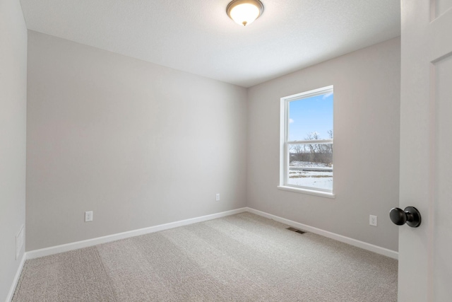 empty room featuring visible vents, baseboards, and carpet