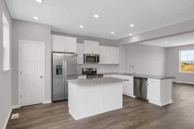 kitchen with sink, stainless steel appliances, white cabinetry, and a kitchen island