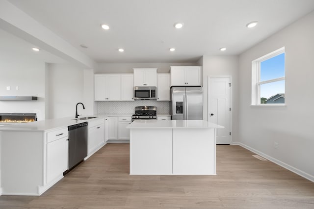 kitchen featuring sink, white cabinets, light hardwood / wood-style flooring, and stainless steel appliances