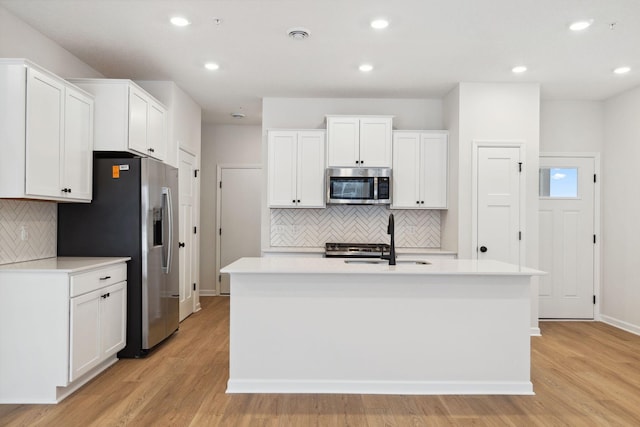 kitchen with stainless steel appliances, an island with sink, sink, and white cabinets