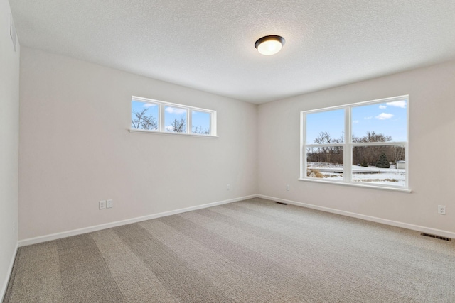 carpeted spare room featuring a textured ceiling