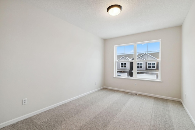 carpeted empty room with a textured ceiling