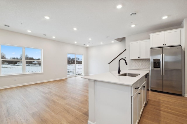 kitchen with tasteful backsplash, white cabinetry, sink, a kitchen island with sink, and stainless steel fridge with ice dispenser