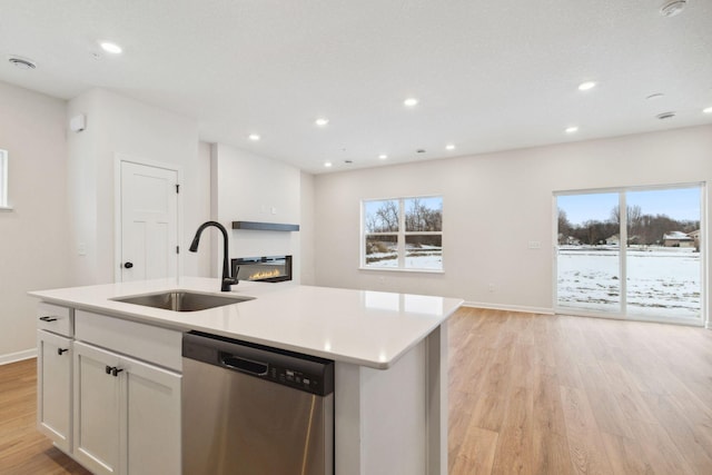 kitchen with sink, white cabinetry, light hardwood / wood-style flooring, dishwasher, and a kitchen island with sink