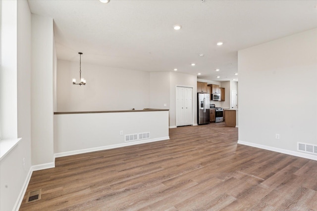 unfurnished living room with a chandelier and light hardwood / wood-style floors