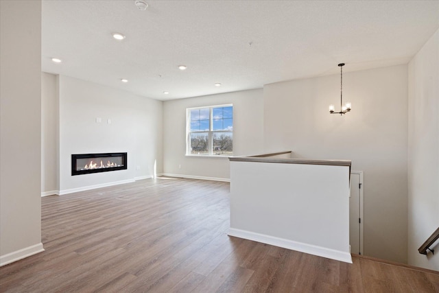 unfurnished living room with hardwood / wood-style floors and an inviting chandelier