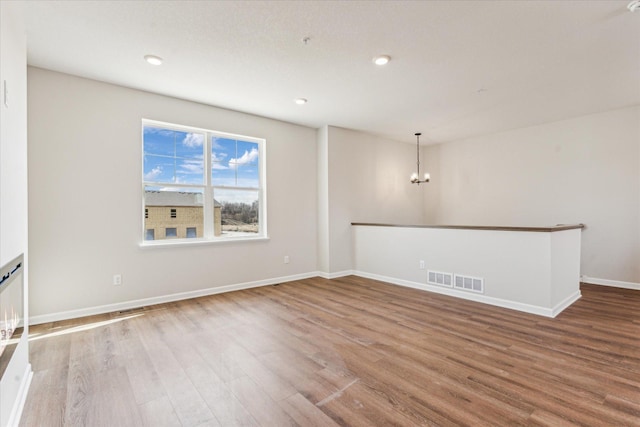 unfurnished room featuring a notable chandelier and wood-type flooring