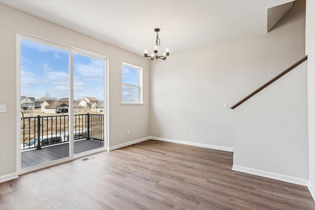 empty room featuring wood-type flooring and a chandelier