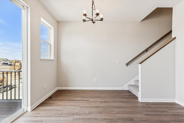 unfurnished dining area featuring an inviting chandelier, hardwood / wood-style flooring, and plenty of natural light