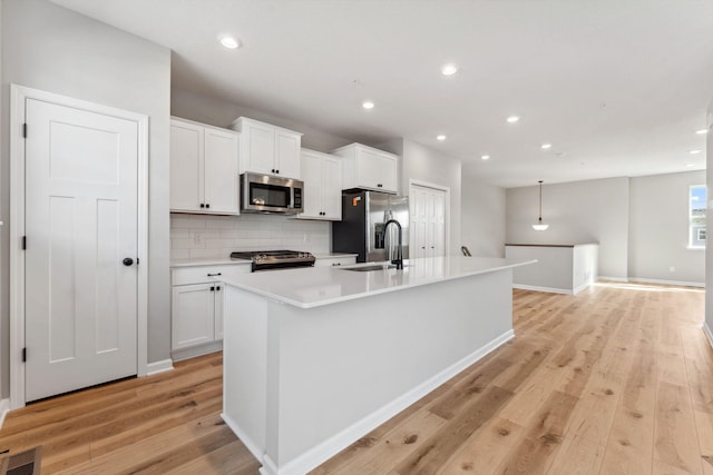 kitchen featuring visible vents, light wood-style flooring, appliances with stainless steel finishes, white cabinetry, and a kitchen island with sink