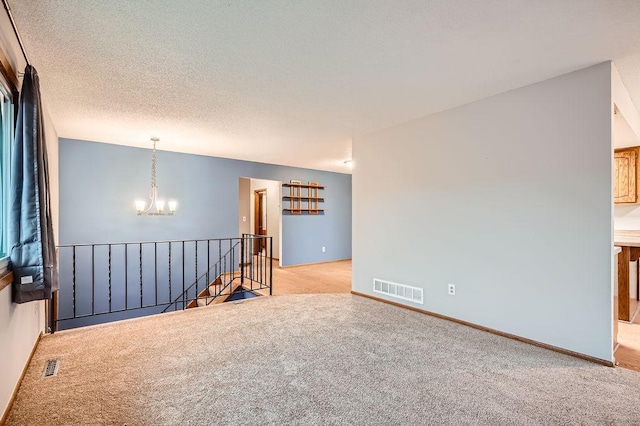 carpeted spare room with an inviting chandelier