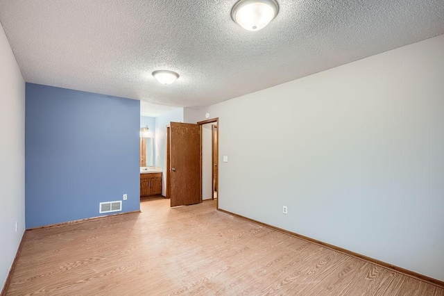 spare room featuring light hardwood / wood-style floors and a textured ceiling