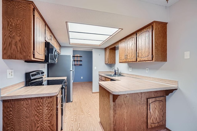 kitchen featuring appliances with stainless steel finishes, a kitchen bar, sink, kitchen peninsula, and light hardwood / wood-style flooring