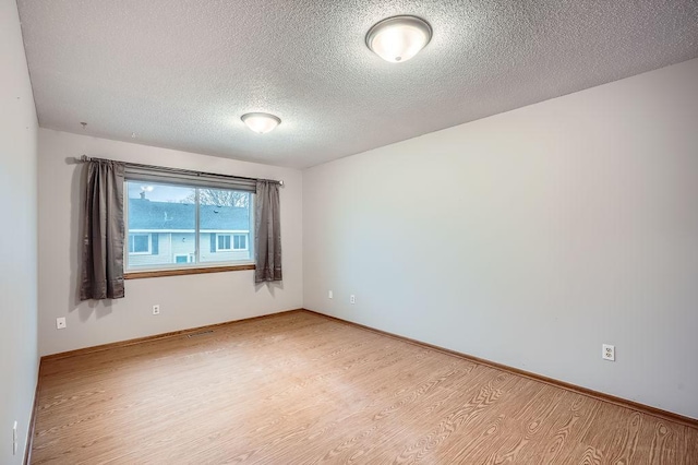 spare room with a textured ceiling and light wood-type flooring