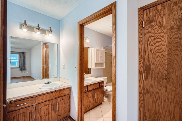 bathroom with toilet, a textured ceiling, tile patterned flooring, and vanity