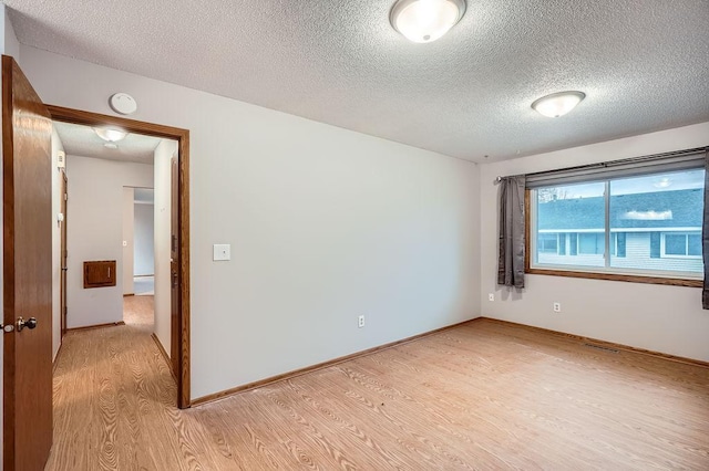 unfurnished room with light hardwood / wood-style floors and a textured ceiling