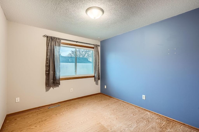 spare room featuring light hardwood / wood-style flooring and a textured ceiling