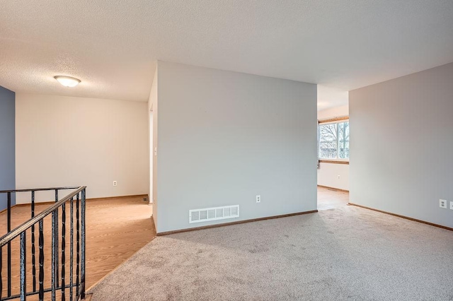 spare room with light colored carpet and a textured ceiling