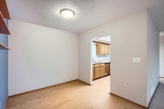 spare room with sink, a textured ceiling, and light hardwood / wood-style flooring