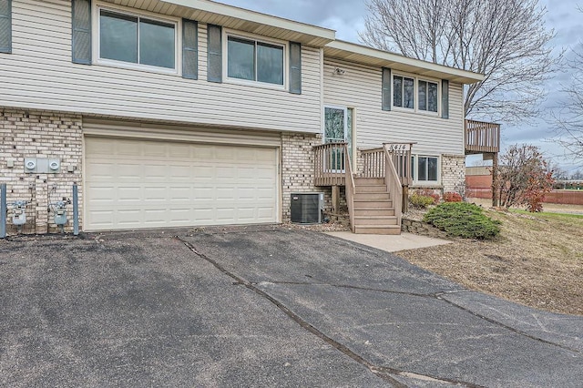 bi-level home featuring central air condition unit and a garage