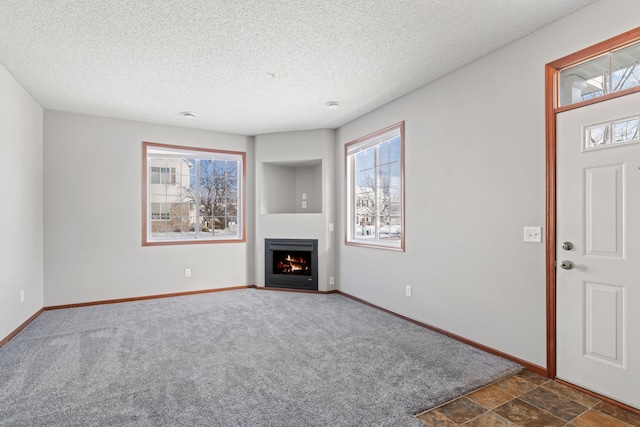 unfurnished living room with dark carpet and a textured ceiling