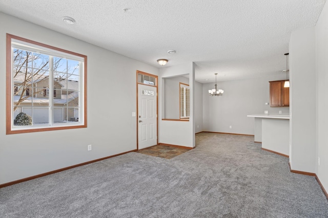 unfurnished living room featuring a textured ceiling, an inviting chandelier, and light colored carpet